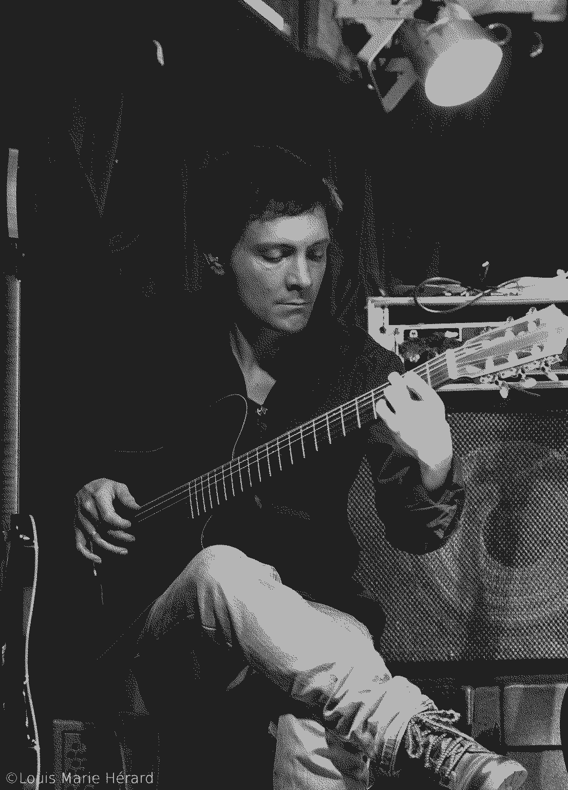 Picture of Clément Bertine, sitting, playing the guitar